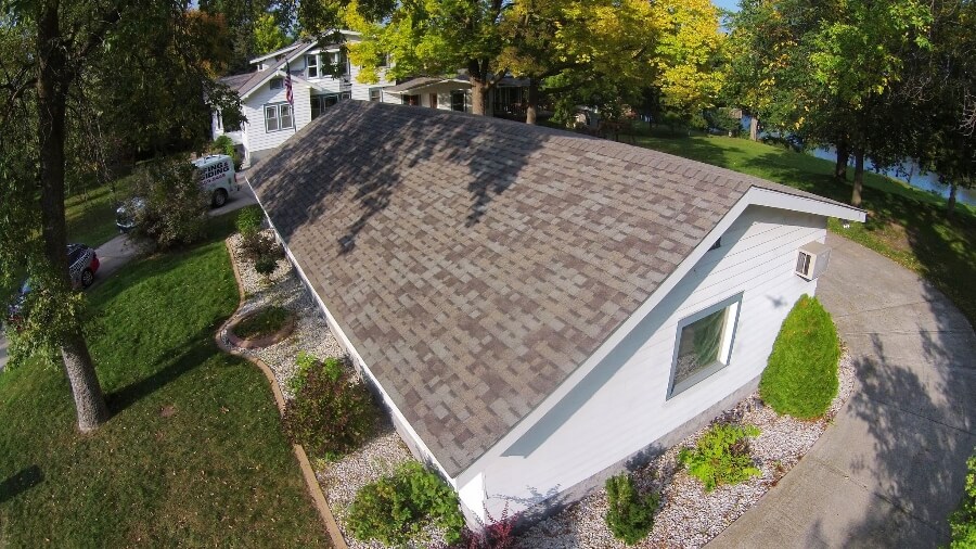 A weathered-wood blend shingle roof on a single-story home with stone landscaping.